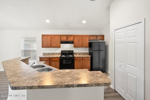 kitchen featuring sink, dark wood-type flooring, black appliances, and a center island with sink