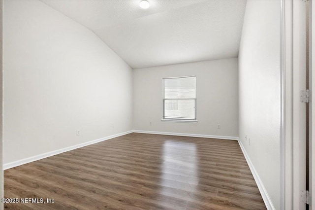 empty room with dark hardwood / wood-style flooring, lofted ceiling, and a textured ceiling