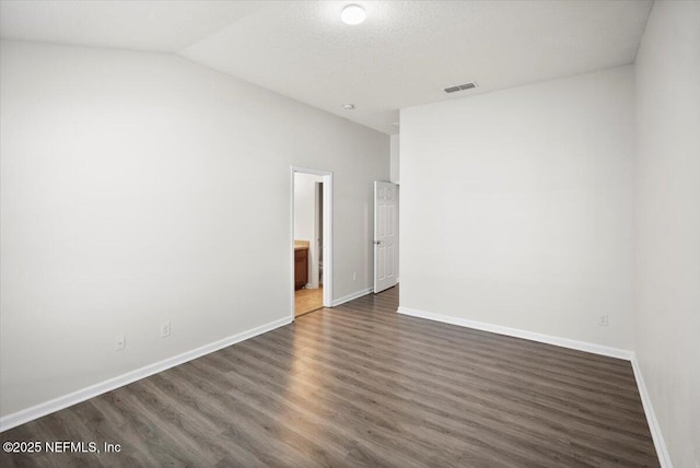 unfurnished room with dark wood-type flooring, a textured ceiling, and vaulted ceiling