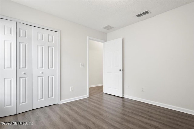 unfurnished bedroom featuring hardwood / wood-style flooring, a textured ceiling, and a closet