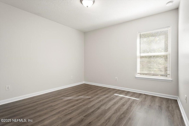 unfurnished room featuring a textured ceiling and dark hardwood / wood-style flooring