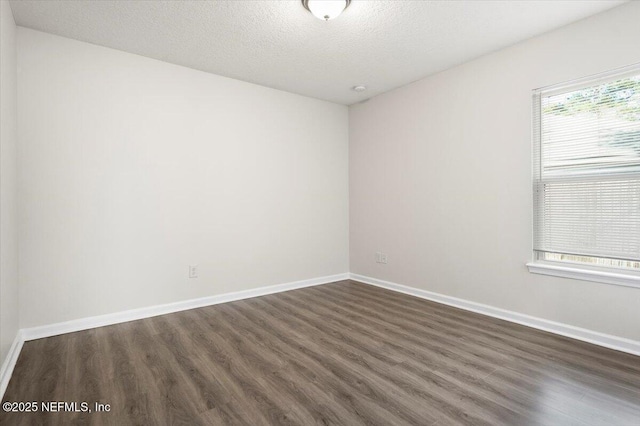 spare room with a textured ceiling and dark hardwood / wood-style flooring