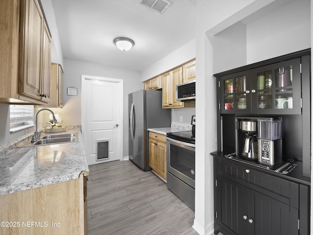 kitchen featuring appliances with stainless steel finishes, sink, and light wood-type flooring