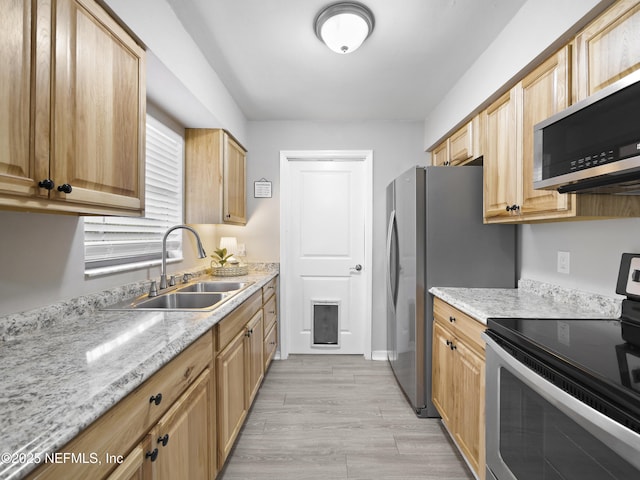 kitchen featuring light stone counters, stainless steel appliances, sink, and light hardwood / wood-style flooring