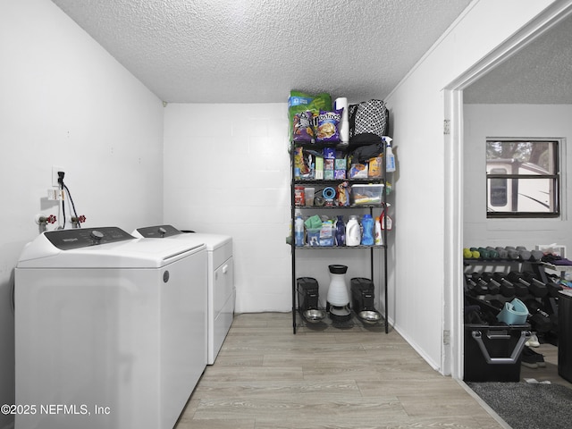 laundry room featuring washer and clothes dryer, a textured ceiling, and light wood-type flooring