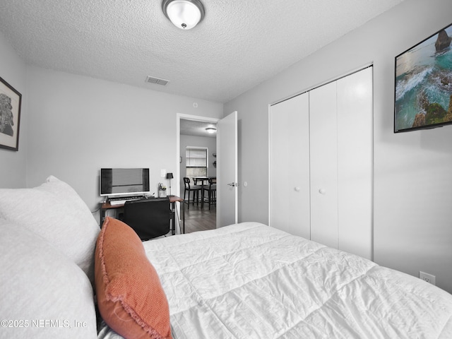 bedroom featuring wood-type flooring, a closet, and a textured ceiling