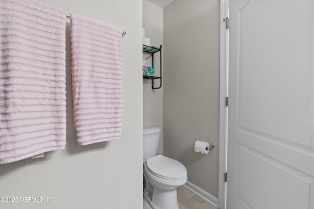 bathroom with baseboards, toilet, and tile patterned floors