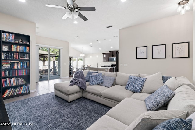 living room with lofted ceiling, visible vents, light tile patterned flooring, ceiling fan, and a textured ceiling