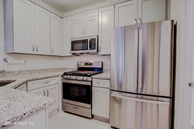 kitchen with stainless steel appliances, white cabinetry, and light stone countertops