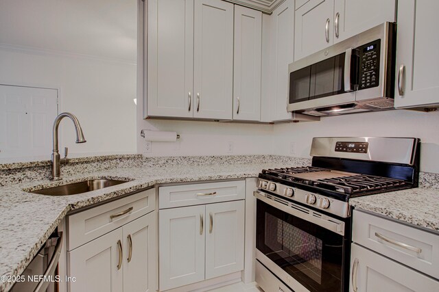 kitchen featuring appliances with stainless steel finishes, light stone countertops, crown molding, sink, and white cabinetry