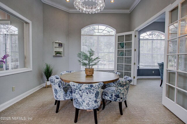 carpeted dining area featuring ornamental molding and an inviting chandelier