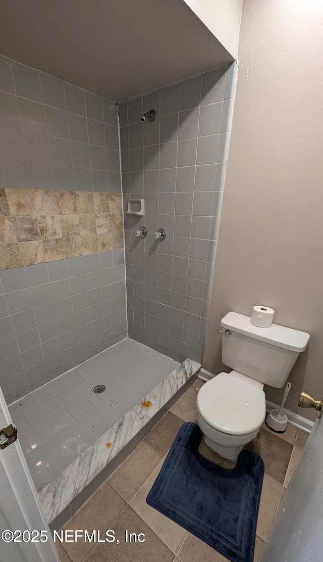 bathroom with tile patterned floors, toilet, and a tile shower