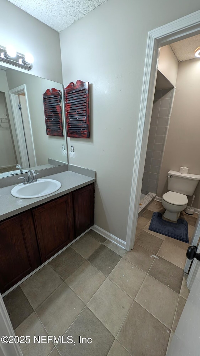 bathroom featuring tile patterned floors, vanity, toilet, and a textured ceiling