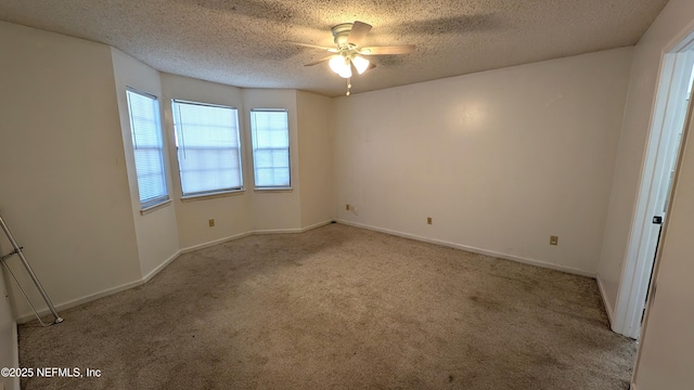 spare room with a textured ceiling, light colored carpet, and ceiling fan