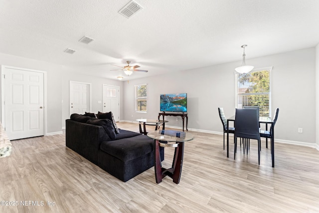 living room with ceiling fan, light hardwood / wood-style floors, and a textured ceiling