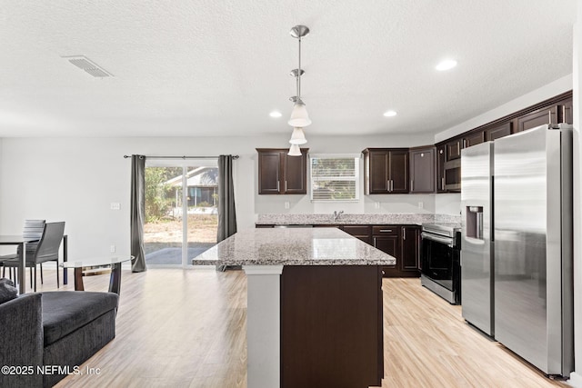 kitchen featuring pendant lighting, appliances with stainless steel finishes, dark brown cabinetry, light hardwood / wood-style floors, and a kitchen island