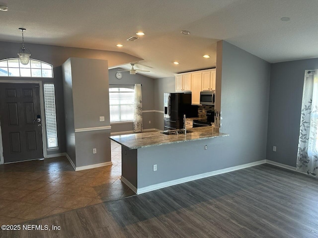 kitchen featuring white cabinetry, kitchen peninsula, pendant lighting, light stone countertops, and black appliances