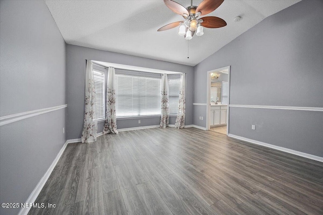 spare room featuring lofted ceiling, dark hardwood / wood-style floors, a textured ceiling, and ceiling fan