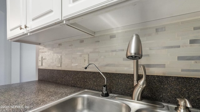 interior details with white cabinetry, backsplash, and sink