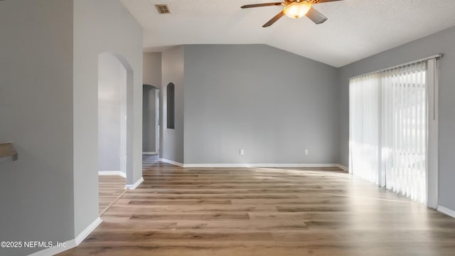 unfurnished room with ceiling fan, lofted ceiling, a textured ceiling, and light wood-type flooring