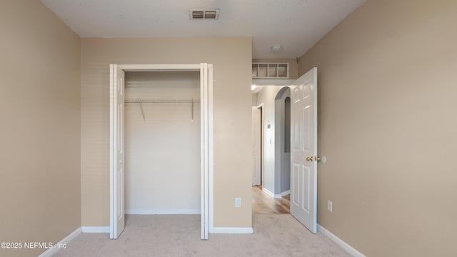 unfurnished bedroom featuring light carpet and a closet