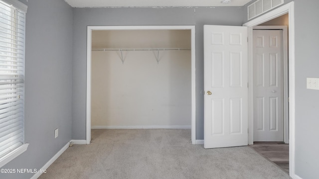 unfurnished bedroom with light colored carpet and a closet