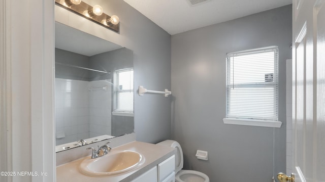 bathroom with vanity, toilet, and a shower