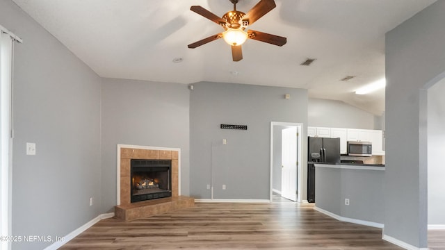 unfurnished living room featuring hardwood / wood-style flooring, a tile fireplace, lofted ceiling, and ceiling fan