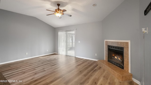 unfurnished living room with hardwood / wood-style flooring, ceiling fan, lofted ceiling, and a fireplace