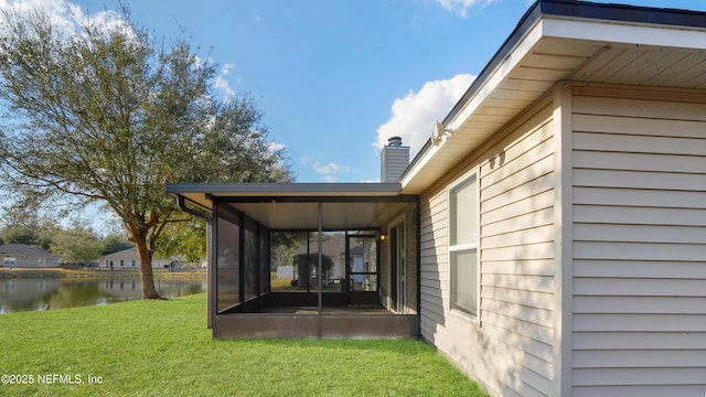 view of yard with a sunroom and a water view