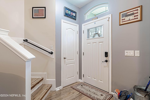 foyer entrance with a textured ceiling and light wood-type flooring