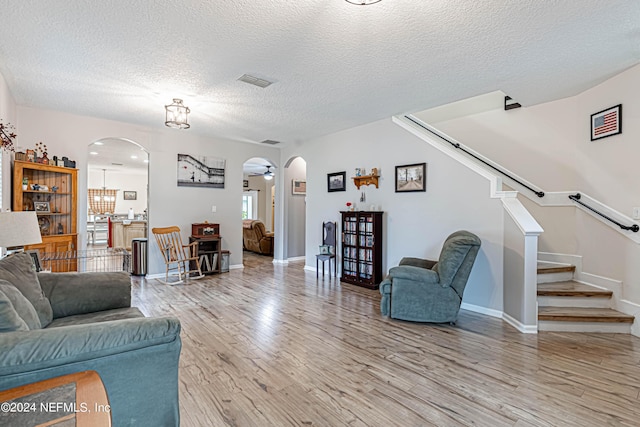 living room featuring ceiling fan, a textured ceiling, and light wood-type flooring