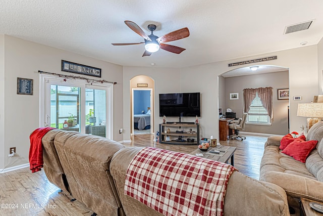 living room with hardwood / wood-style flooring, ceiling fan, and a textured ceiling