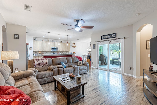 living room with ceiling fan, light hardwood / wood-style floors, and a textured ceiling