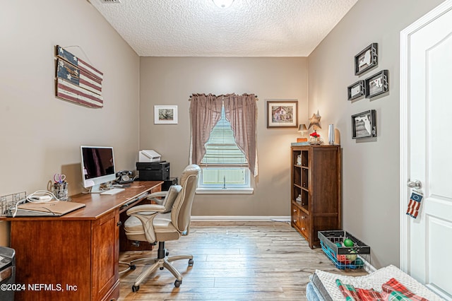 office area with light hardwood / wood-style flooring and a textured ceiling