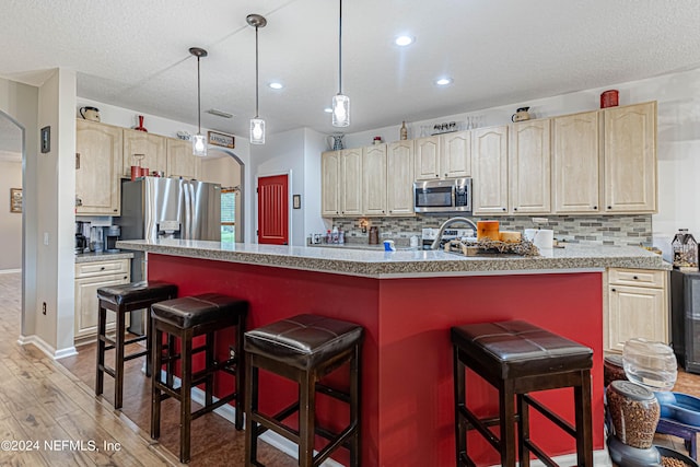 kitchen with a kitchen island, tasteful backsplash, appliances with stainless steel finishes, and hardwood / wood-style flooring