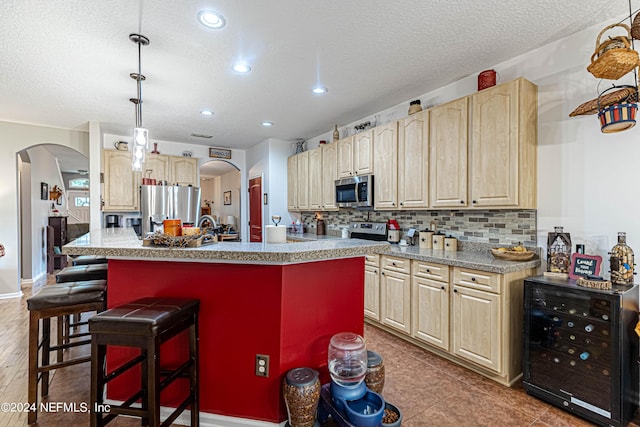 kitchen with light brown cabinetry, backsplash, a kitchen bar, a center island, and stainless steel appliances