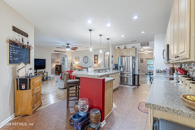 kitchen with a breakfast bar, a center island, hanging light fixtures, light tile patterned floors, and appliances with stainless steel finishes