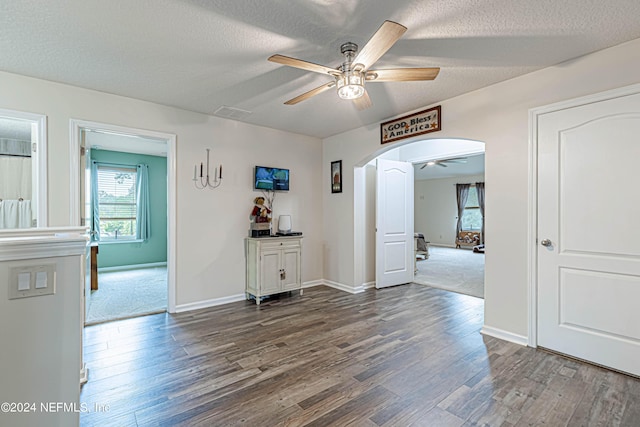 spare room with a textured ceiling, dark wood-type flooring, and ceiling fan