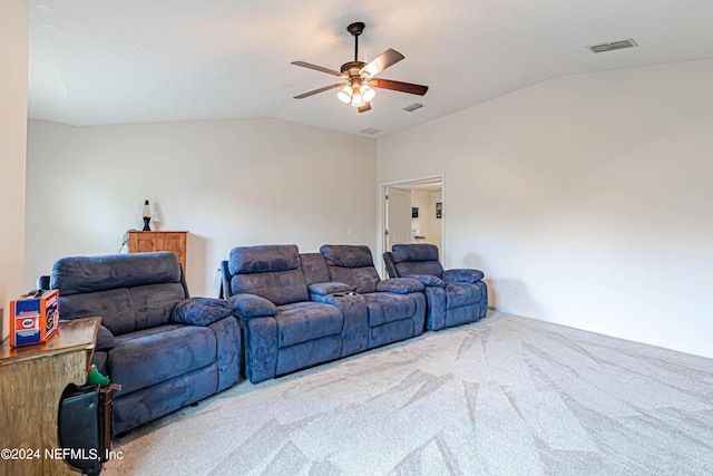 carpeted home theater room with a textured ceiling, vaulted ceiling, and ceiling fan