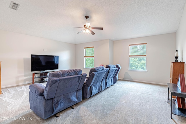 living room with ceiling fan, light colored carpet, and a textured ceiling