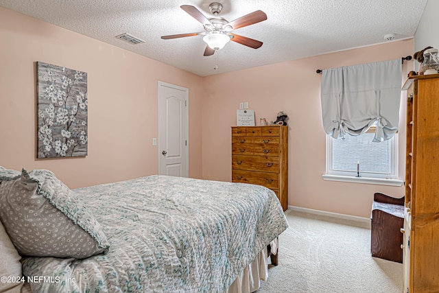 bedroom with light carpet, ceiling fan, and a textured ceiling