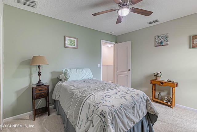 carpeted bedroom with ceiling fan and a textured ceiling