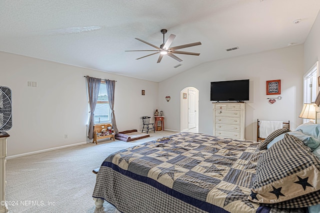 bedroom with ceiling fan, lofted ceiling, carpet floors, and a textured ceiling