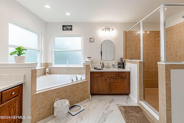 bathroom with vanity, shower with separate bathtub, and a textured ceiling