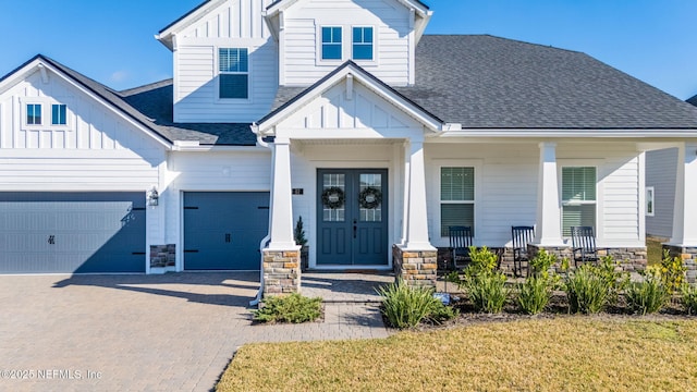 view of front of house with a garage, a front lawn, covered porch, and french doors