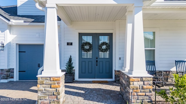 property entrance featuring a garage, covered porch, and french doors