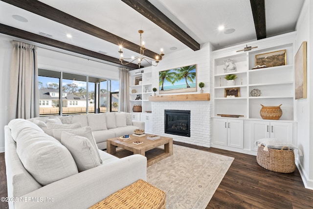 living room featuring dark wood-type flooring, built in features, an inviting chandelier, a brick fireplace, and beamed ceiling