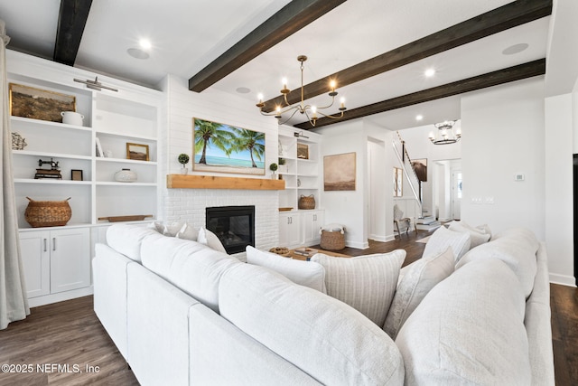 living room with beam ceiling, dark wood-type flooring, a chandelier, and a fireplace