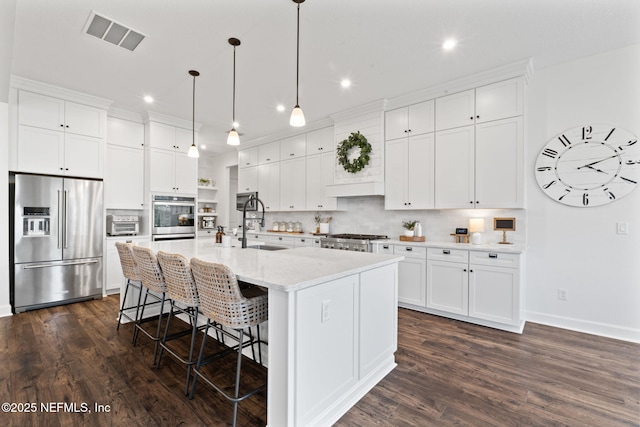 kitchen with an island with sink, white cabinets, and appliances with stainless steel finishes